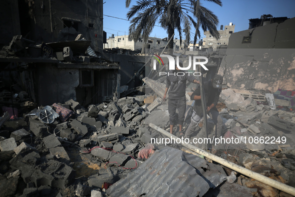 Palestinians are gathering amid the rubble of destroyed buildings following an Israeli bombardment in Deir El-Balah, in the central Gaza Str...