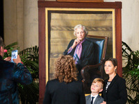 People interact with a portrait of retired Associate Justice Sandra Day O’Connor, the first woman to serve on the Supreme Court, as she lies...