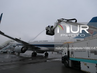 A staff member is driving China's self-developed ice removal mobile terminal system to de-ice the wing of a passenger plane's fuselage at th...