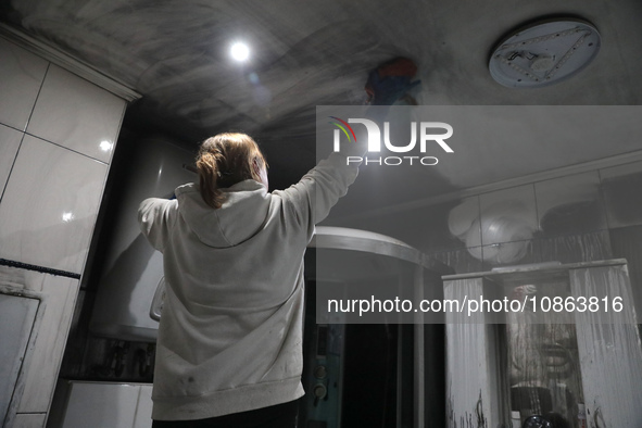 A woman is washing the ceiling in the kitchen of Anatolii Luchok's apartment, which was damaged after the residential building at 4A Ostafii...