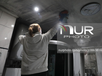 A woman is washing the ceiling in the kitchen of Anatolii Luchok's apartment, which was damaged after the residential building at 4A Ostafii...