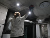 A woman is washing the ceiling in the kitchen of Anatolii Luchok's apartment, which was damaged after the residential building at 4A Ostafii...