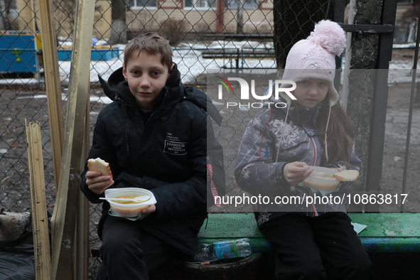 In Kyiv, Ukraine, on December 18, 2023, a boy and a girl are having dinner in the yard outside the residential building at 4A Ostafiia Dashk...