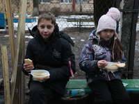 In Kyiv, Ukraine, on December 18, 2023, a boy and a girl are having dinner in the yard outside the residential building at 4A Ostafiia Dashk...