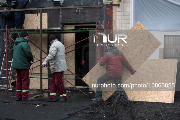 In Kyiv, Ukraine, on December 18, 2023, a man is carrying a particle board to seal a window at the residential building at 4A Ostafiia Dashk...