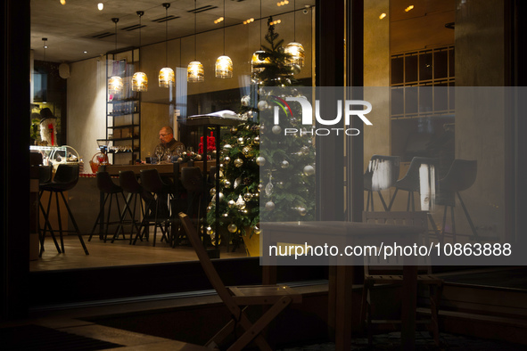 A Christmas tree is being seen through the floor-to-ceiling window of a restaurant at night in Kyiv, Ukraine, on December 18, 2023. 