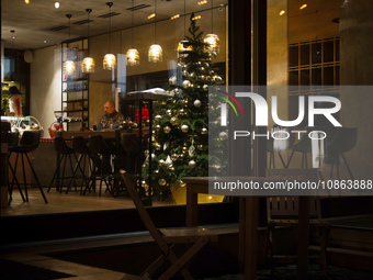 A Christmas tree is being seen through the floor-to-ceiling window of a restaurant at night in Kyiv, Ukraine, on December 18, 2023. (