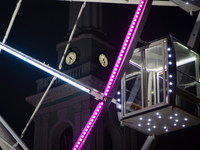 A cabin of the Ferris wheel is seen near a clock tower at night in Kontraktova Square, Kyiv, Ukraine, on December 18, 2023. (