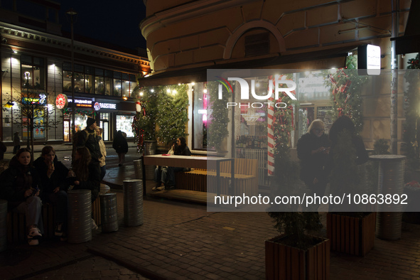 Visitors are staying at an outdoor space of a cafe at night in Kyiv, Ukraine, on December 18, 2023. 