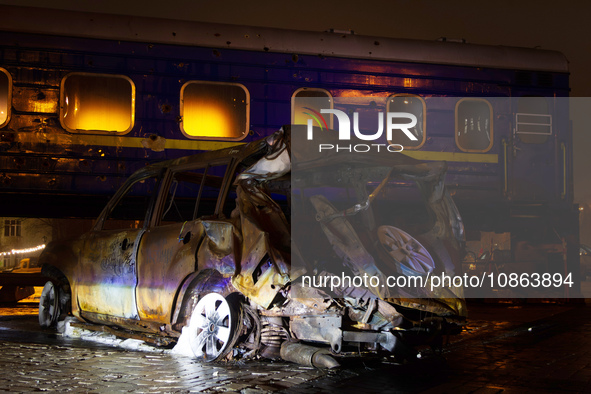 A wrecked car is being displayed in front of the Ukrzaliznytsia (Ukrainian Railways) train carriage, which was used for the evacuation of ci...