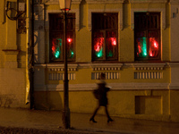 A woman is walking past an old building while red and green lights are illuminating three windows at night in Kyiv, Ukraine, on December 18,...