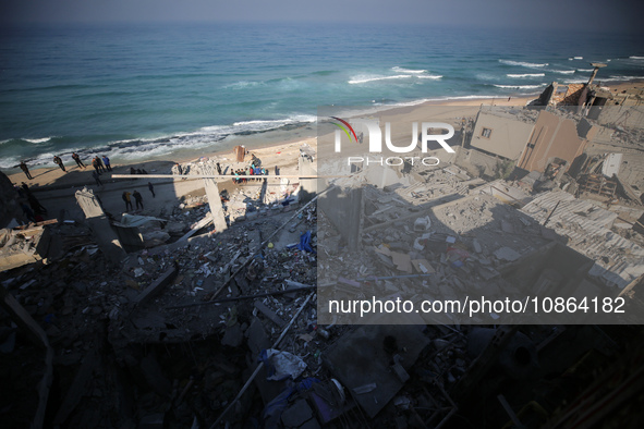 Palestinians are gathering amid the rubble of destroyed buildings following an Israeli bombardment in Deir El-Balah, in the central Gaza Str...