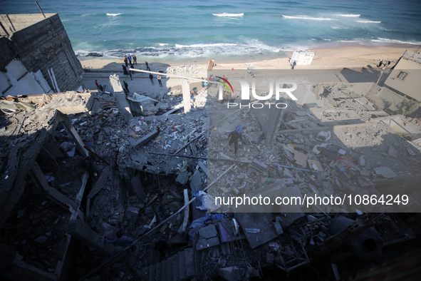 Palestinians are gathering amid the rubble of destroyed buildings following an Israeli bombardment in Deir El-Balah, in the central Gaza Str...