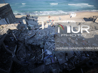 Palestinians are gathering amid the rubble of destroyed buildings following an Israeli bombardment in Deir El-Balah, in the central Gaza Str...