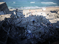 Palestinians are gathering amid the rubble of destroyed buildings following an Israeli bombardment in Deir El-Balah, in the central Gaza Str...