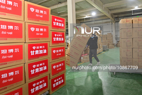 A staff member at a down jacket manufacturer is hauling down jackets to support the quake-hit areas of Jishishan County in Qingzhou, Shandon...