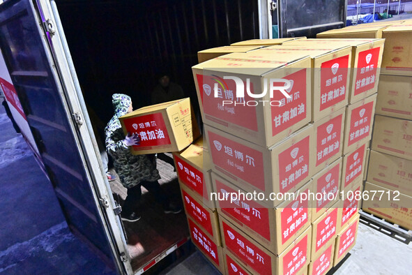 Staff members at a down jacket manufacturer are loading down jackets onto a truck to support the quake-hit areas of Jishishan County in Qing...