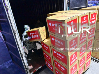 Staff members at a down jacket manufacturer are loading down jackets onto a truck to support the quake-hit areas of Jishishan County in Qing...