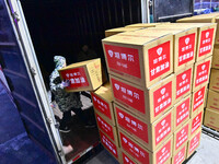 Staff members at a down jacket manufacturer are loading down jackets onto a truck to support the quake-hit areas of Jishishan County in Qing...