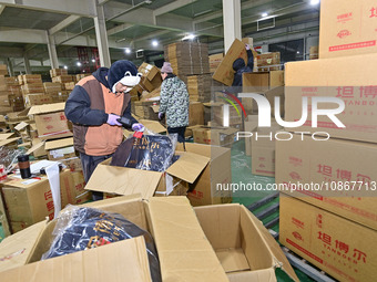 Staff members at a down jacket manufacturer are packaging down jackets to support the quake-hit areas of Jishishan County in Qingzhou, Shand...