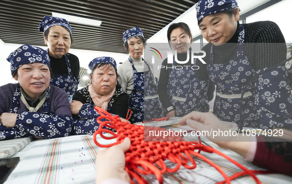 A teacher is teaching students how to knit Chinese knots at a vocational training school on Dexi Street in Zouping, China, on December 25, 2...