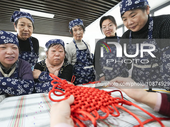 A teacher is teaching students how to knit Chinese knots at a vocational training school on Dexi Street in Zouping, China, on December 25, 2...