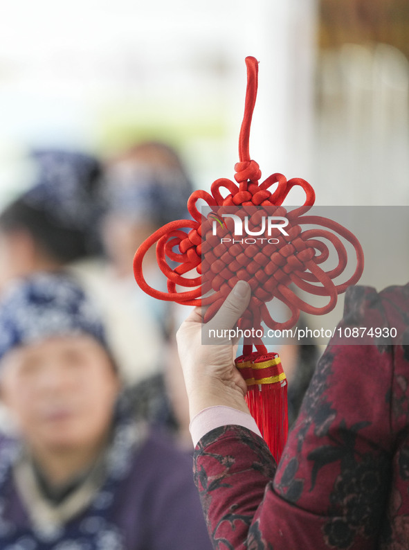 A teacher is teaching students how to knit Chinese knots at a vocational training school on Dexi Street in Zouping, China, on December 25, 2...