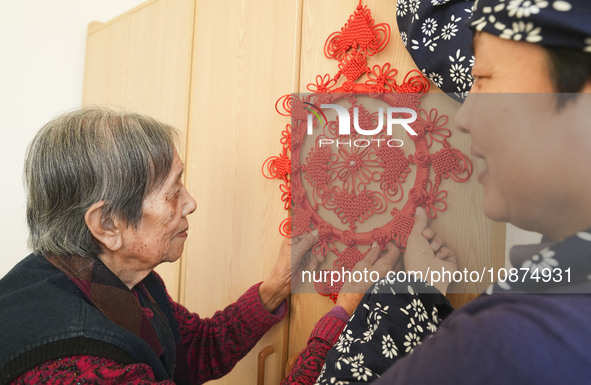 A student is presenting a Chinese knot to an elderly person at a nursing home on Huangshan Street in Zouping, China, on December 25, 2023. 