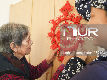 A student is presenting a Chinese knot to an elderly person at a nursing home on Huangshan Street in Zouping, China, on December 25, 2023. (