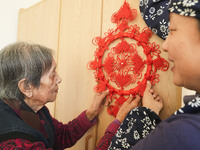 A student is presenting a Chinese knot to an elderly person at a nursing home on Huangshan Street in Zouping, China, on December 25, 2023. (