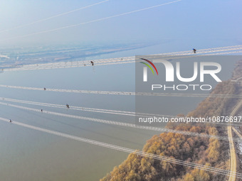 Construction workers are performing an acceptance check on the 200 kV DC transmission line project, which is 100 meters high, in Yangzhou, J...