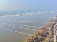 Construction workers are performing an acceptance check on the 200 kV DC transmission line project, which is 100 meters high, in Yangzhou, J...