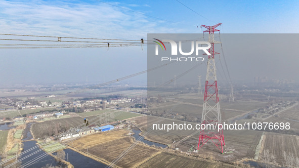 Construction workers are performing an acceptance check on the 200 kV DC transmission line project, which is 100 meters high, in Yangzhou, J...