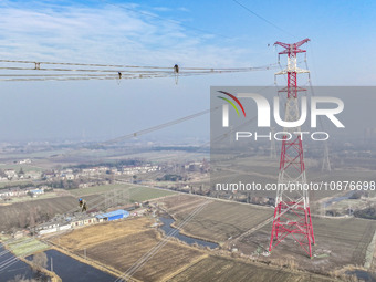 Construction workers are performing an acceptance check on the 200 kV DC transmission line project, which is 100 meters high, in Yangzhou, J...