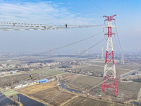 Construction workers are performing an acceptance check on the 200 kV DC transmission line project, which is 100 meters high, in Yangzhou, J...