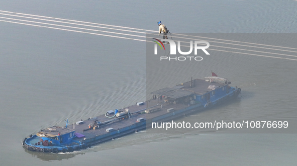 Construction workers are performing an acceptance check on the 200 kV DC transmission line project, which is 100 meters high, in Yangzhou, J...