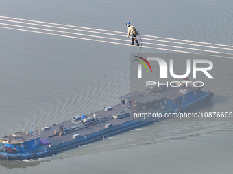 Construction workers are performing an acceptance check on the 200 kV DC transmission line project, which is 100 meters high, in Yangzhou, J...