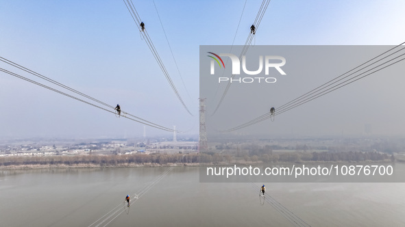 Construction workers are performing an acceptance check on the 200 kV DC transmission line project, which is 100 meters high, in Yangzhou, J...