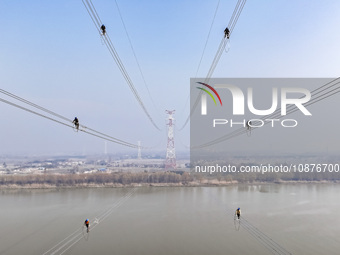 Construction workers are performing an acceptance check on the 200 kV DC transmission line project, which is 100 meters high, in Yangzhou, J...