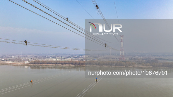 Construction workers are performing an acceptance check on the 200 kV DC transmission line project, which is 100 meters high, in Yangzhou, J...