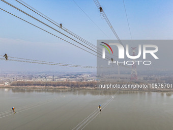 Construction workers are performing an acceptance check on the 200 kV DC transmission line project, which is 100 meters high, in Yangzhou, J...