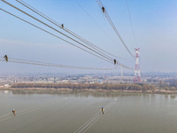 Construction workers are performing an acceptance check on the 200 kV DC transmission line project, which is 100 meters high, in Yangzhou, J...