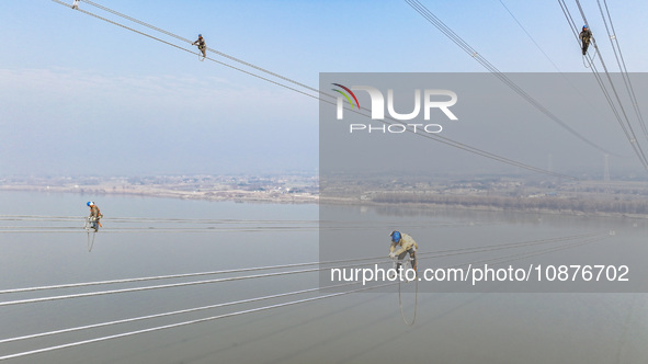 Construction workers are performing an acceptance check on the 200 kV DC transmission line project, which is 100 meters high, in Yangzhou, J...