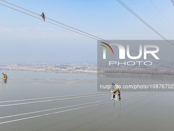 Construction workers are performing an acceptance check on the 200 kV DC transmission line project, which is 100 meters high, in Yangzhou, J...