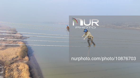 Construction workers are performing an acceptance check on the 200 kV DC transmission line project, which is 100 meters high, in Yangzhou, J...