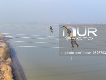 Construction workers are performing an acceptance check on the 200 kV DC transmission line project, which is 100 meters high, in Yangzhou, J...