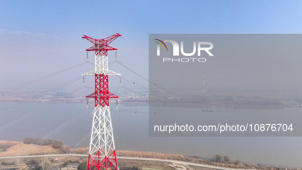 Construction workers are performing an acceptance check on the 200 kV DC transmission line project, which is 100 meters high, in Yangzhou, J...