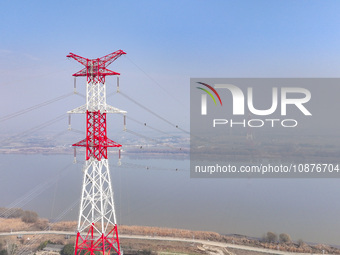 Construction workers are performing an acceptance check on the 200 kV DC transmission line project, which is 100 meters high, in Yangzhou, J...