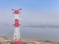 Construction workers are performing an acceptance check on the 200 kV DC transmission line project, which is 100 meters high, in Yangzhou, J...