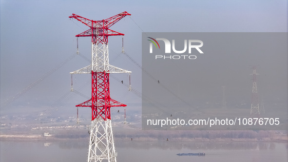 Construction workers are performing an acceptance check on the 200 kV DC transmission line project, which is 100 meters high, in Yangzhou, J...